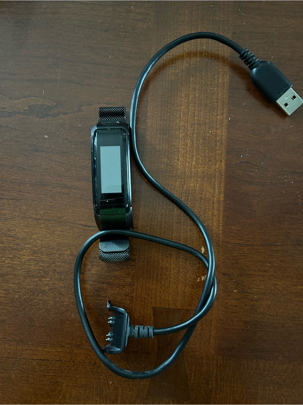 Garmin vívosmart HR fitness activity tracker along with its charging cable.